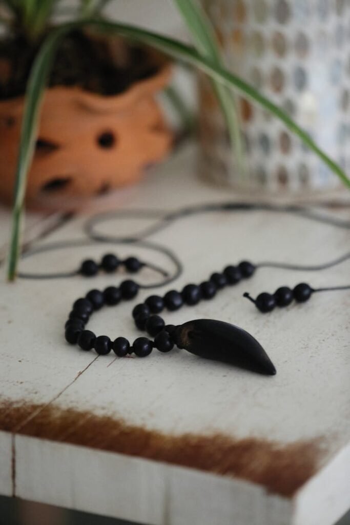 Stylish black beaded necklace with pendant on a rustic table, perfect for bohemian fashion.