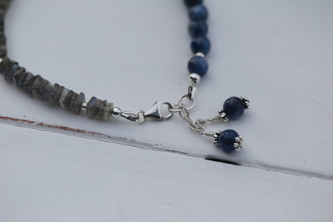 Close-up of a gemstone bracelet featuring beads and silver metalwork on a white surface.