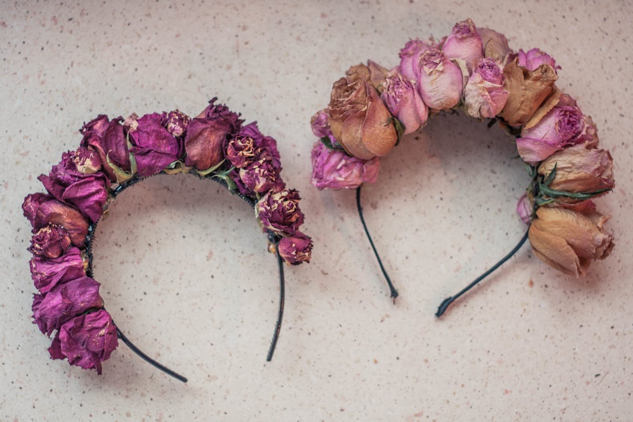 Two retro floral headbands adorned with dried roses, showcasing a vintage design aesthetic.