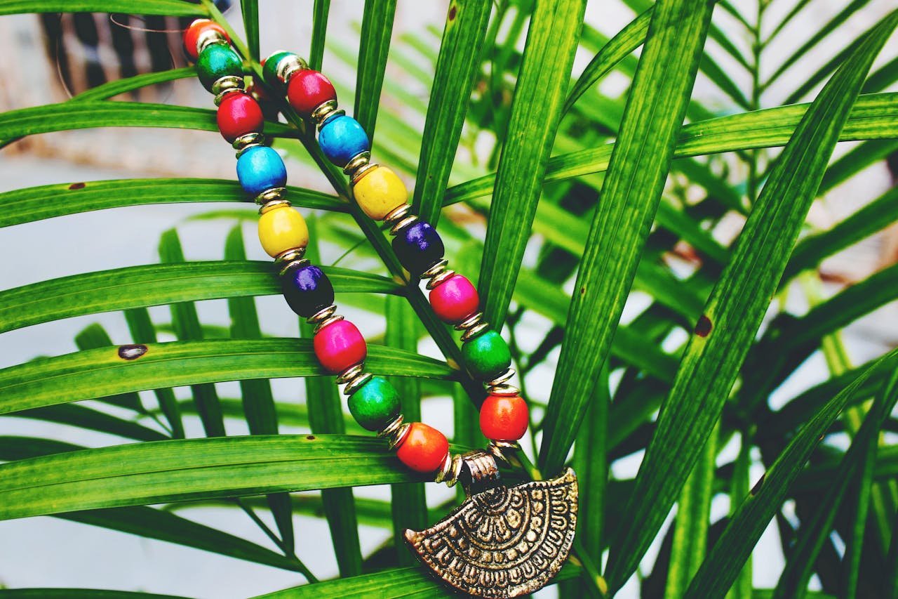 Vibrant handcrafted necklace with colorful beads resting on green palm leaves, showcasing traditional design.