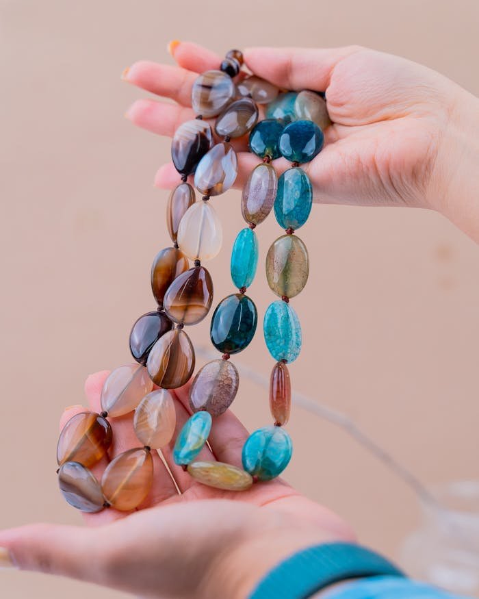 Colorful gemstone necklace held by hands, showcasing intricate beads and handmade craftsmanship.